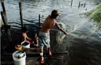 Autor: Guilherme Bergamini
Moradores às margens de um rio, com um homem lançando uma rede de pesca em área ribeirinha